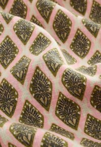 Bomullstyg med en rosa bakgrund, som har ett upprepat diamantmönster i olivgrön och mörkblåa blommönster. Mjuk textur.