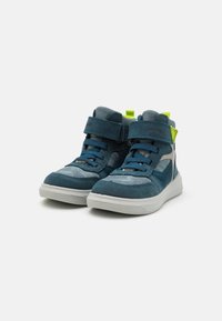 Blå ruskinn høy-top sneakers med hvit gummisåle, med borrelåsremmer og en lys grønn aksent på hælen.