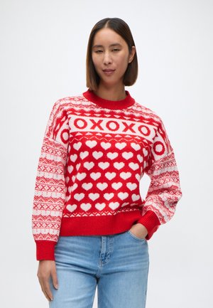 Red knit sweater with white heart patterns and 'XOXO' text, featuring a ribbed neckline and cuffs, with a soft texture and relaxed fit.