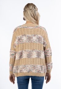 Texturerad stickad tröja i tan med randiga detaljer i pastellfärger. Har en avslappnad passform och sänkta axlar för komfort.
