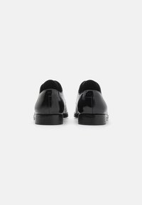 Pantofi din piele neagră cu un finisaj neted și strălucitor, având vârful rotund și toc negru, scăzut și robust. Design simplu, fără aplicații.