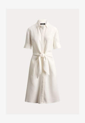 Balta lininė suknelė marškinio stiliumi su apykakle, trumpomis rankovėmis ir priekyje surišama juosmens detalė. Apdaila su sagomis priekyje.