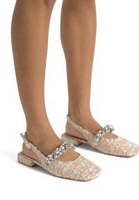 Scarpe in tweed rosa con tacco piatto, caratterizzate da un cinturino gioiello sul collo del piede e dettagli in tessuto testurizzato sulla parte superiore.
