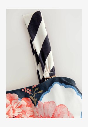 Virágmintás kézitáska sötétkék alappal, rózsaszín és fehér virágokkal. A pánt fekete-fehér csíkos, aranyszínű fémrészekkel.