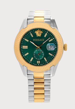 Montre-bracelet Versace avec cadran vert, bracelet métal or et argent, lunette dorée, affichage de la date à 3 heures, et logo Versace à 12 heures.