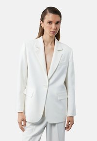 Weißer taillierter Blazer mit einem einzelnen Knopfverschluss, Reverskragen und zwei vorderen Taschen, aus einem strukturierten Stoff für ein elegantes Aussehen.