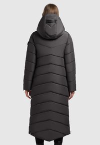 Long puffer coat in dark gray with chevron padding, a large hood, and a branded back detail. Features pockets and a slightly curved hem.