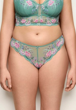 Grüner Spitzen-BH und passende Unterhose mit rosa und lila Blumenstickerei auf dem Oberkörper und den oberen Oberschenkeln einer Frau.
