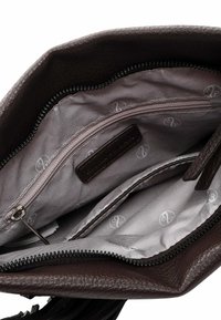 Brown leather handbag interior with two zippered pockets, gray lining featuring a subtle logo pattern, and a textured finish.