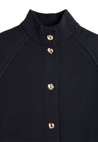 Marineblå strikket cardigan med høy krage, med fem gulltonede knapper foran og raglanermer for en tettsittende silhuett.