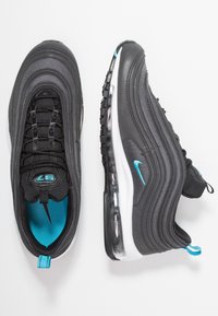 Schwarze Sportschuhe aus Mesh- und Ledermaterialien, mit einer sichtbaren Luftpolsterung, blauen Akzenten und strukturierten Sohlen.