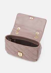 Quiltad mauve läderhandväska med guldkedjestraps och fyrkantig guldspänne, öppen för att visa den mjuka inredningen och innerfickan.