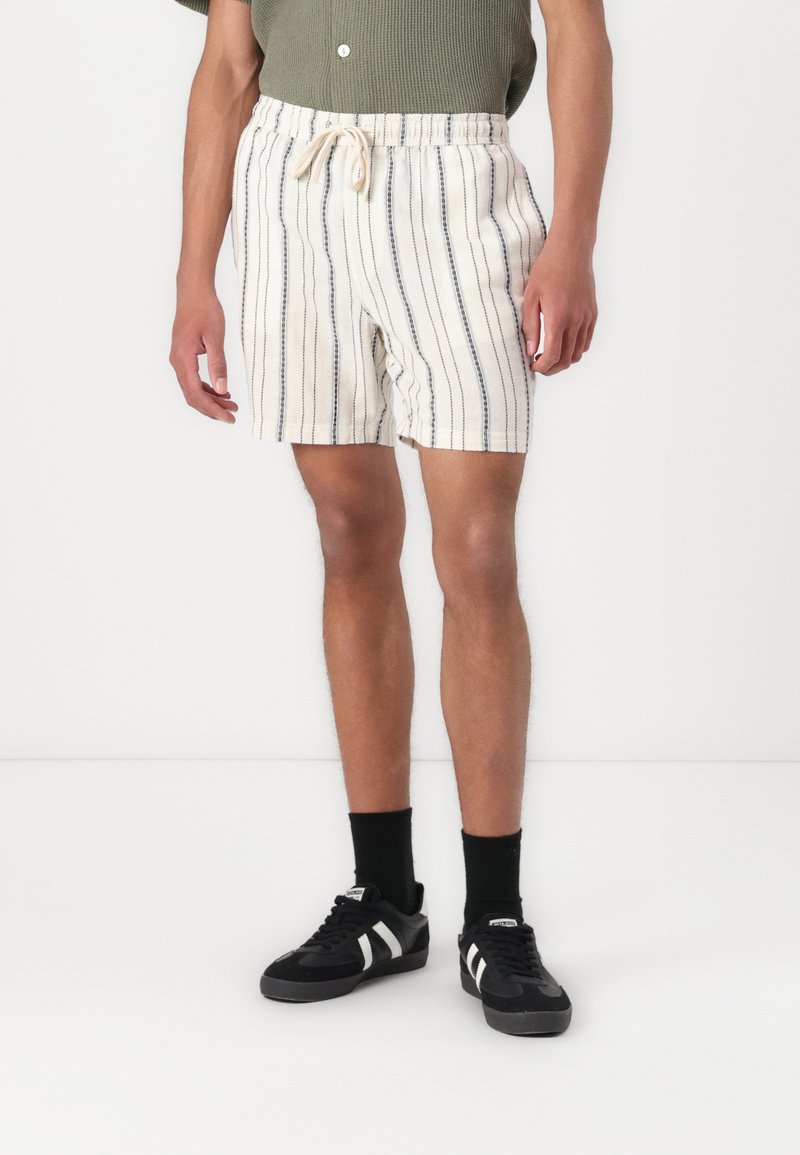 Shorts rayés beige et bleu marine pour homme avec taille élastique et cordon de serrage. Fabriqués en tissu léger, dotés de poches latérales et d'une coupe décontractée.