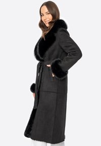 Abrigo de ante negro con un amplio cuello y puños de pelo sintético, cinturón en la cintura, diseño de longitud media y textura suave.