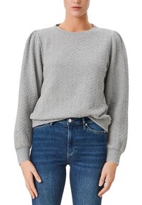Grau strukturierter Pullover mit Fischgrätmuster, rundem Ausschnitt und puffigen langen Ärmeln, kombiniert mit dunkelblauen, eng anliegenden Jeans.