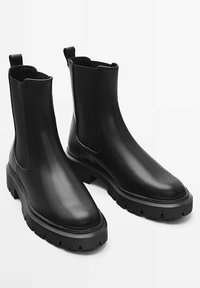 Stivaletti Chelsea in pelle nera con pannelli laterali elasticizzati, punta rotonda e suola in gomma spessa con scanalature profonde per una migliore aderenza.