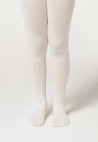 Weiße Strumpfhosen mit einem Muster aus kleinen goldenen Punkten, hergestellt aus einem glatten, elastischen Stoff, der eng am Bein anliegt.
