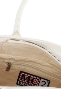 Interno di una borsa bianca con tasca con cerniera, fodera color crema e toppa con logo nero e rosso visibile sul lato interno. Dettaglio della chiusura con cerniera mostrato.