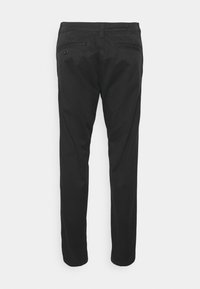Pantaloni neri con vestibilità slim, dotati di due tasche posteriori e una texture liscia. La cintura presenta un discreto dettaglio del logo.