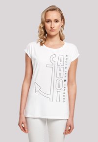 White T-shirt with black graphic print of "AHOI" and an anchor design. Short sleeves, round neckline, soft fabric, casual fit.