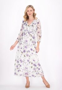 Lange, vloeiende maxi-jurk van doorschijnende witte stof, met paarse bloemenpatronen, een V-halslijn en ruches op het lijfje.