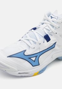 Chaussure de sport blanche avec des accents bleus, texture en maille et design complexe. Ses caractéristiques incluent une semelle rembourrée et un logo bien en vue.