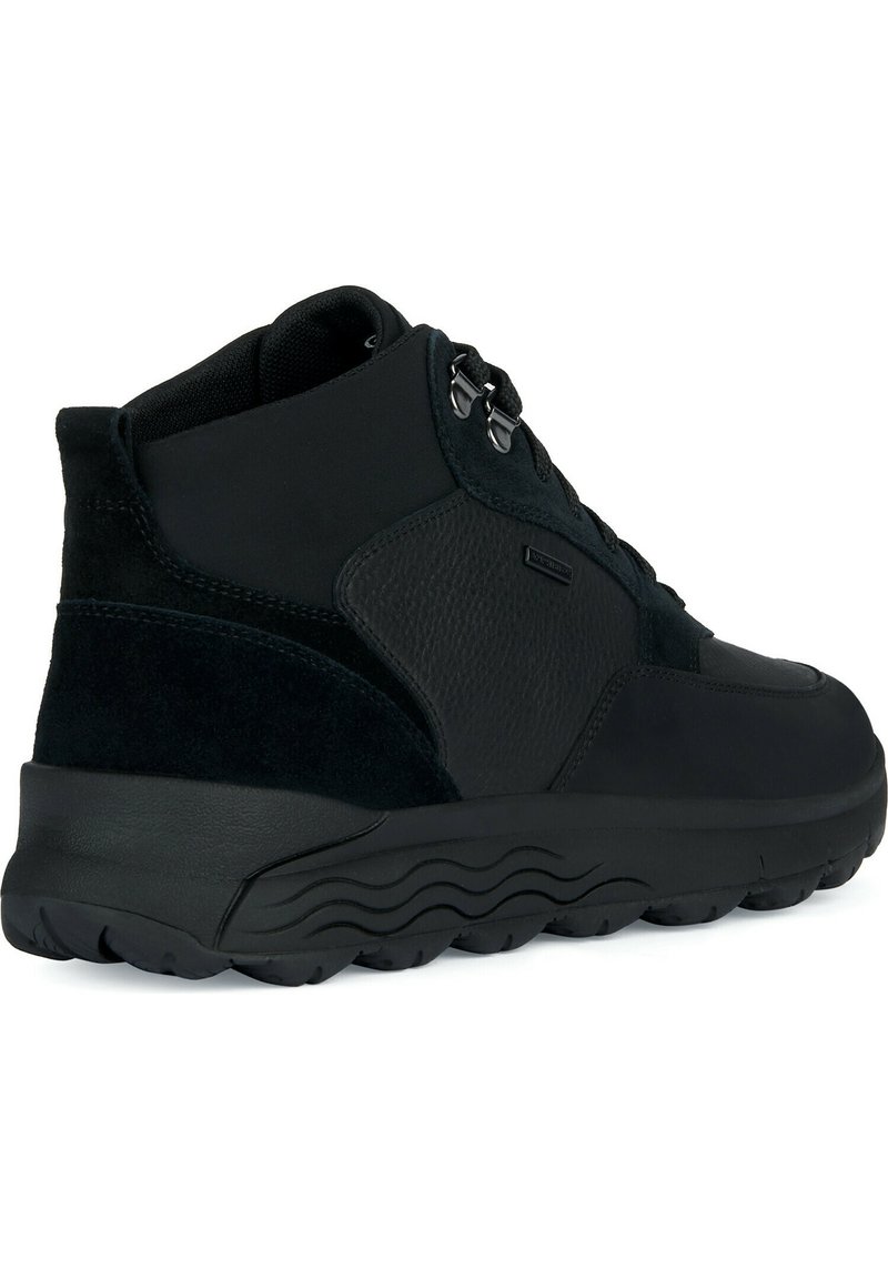 Schwarze High-Top-Sneaker aus einer Mischung aus glattem Leder und Wildleder, mit runder Zehenform, Schnürverschluss und strukturiertem Gummisohle mit Wellenmustern.