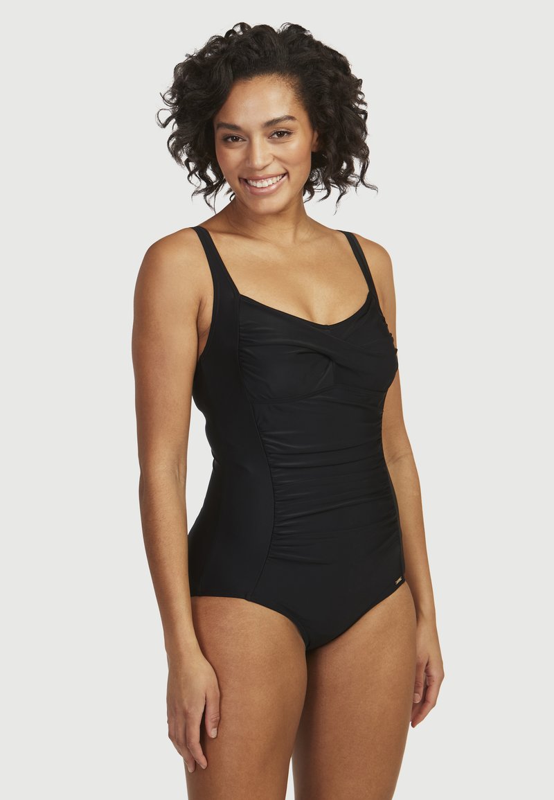 Musta uimapuku, jossa on ohuet olkaimet, rypytetty yksityiskohta rinnassa ja sileä pinta. Sopii uimaan ja rannalla tekemiseen.