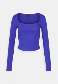 Dopasowana bluzka z długim rękawem w intensywnym odcieniu purpury, wykonana z materiału ribbed. Posiada kwadratowy dekolt i strukturalne szwy, krótki krój.