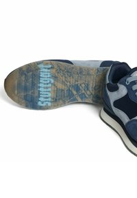 Mörkblå och grå sneaker som visar sulan med en blå "Stuttgart" text överlappning och ett stadslandskap mönster på botten.