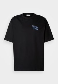 T-shirt en coton noir à coupe décontractée, avec des manches courtes et un logo "Calvin Klein" brodé en bleu sur la poitrine.