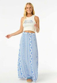 Falda maxi de color azul claro con patrones geométricos blancos, con cintura ajustable mediante cordón. Combinada con una camiseta corta blanca y sandalias.