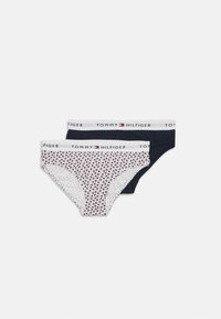 Twee paar Tommy Hilfiger bikini slips: één wit met een kleurrijk bloemenpatroon en één effen marineblauw, beide met een logo tailleband.