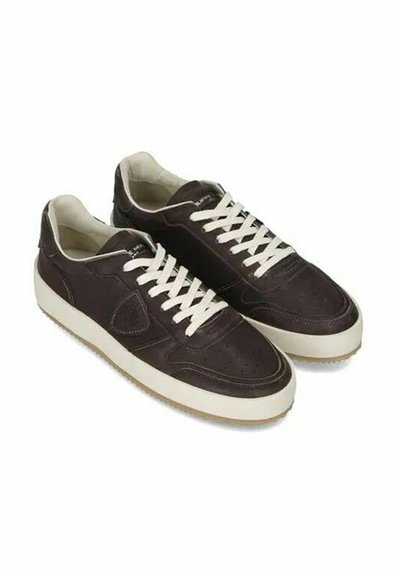 Sneaker in pelle marrone con lacci e suola bianchi. Presenta un design perforato sulla punta e una suola in gomma testurizzata.