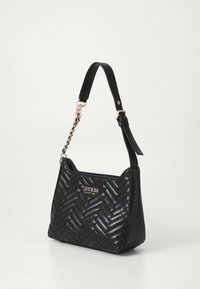 Sac à main en cuir noir avec un motif en chevrons, un accent logo doré, une lanière courte réglable et un détail en chaîne sur la bandoulière.