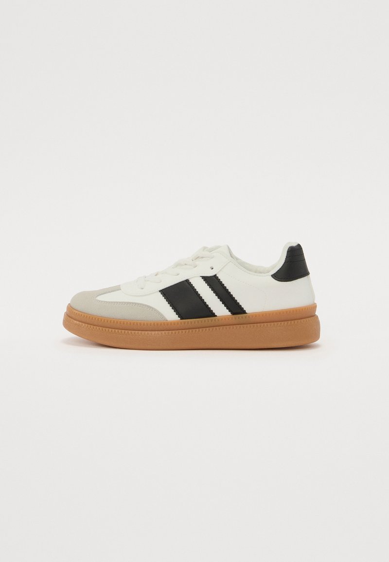 Adidași albi și negri cu un superior texturat, guler umplut și talpă din cauciuc natural. Au trei accente cu dungi pe lateral.