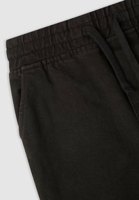 Czarne dresowe spodnie z tkaniny o fakturze, z elastycznym pasem i sznurkiem do regulacji. Posiada boczne kieszenie oraz prążkowaną, kontrastową fakturę u góry.