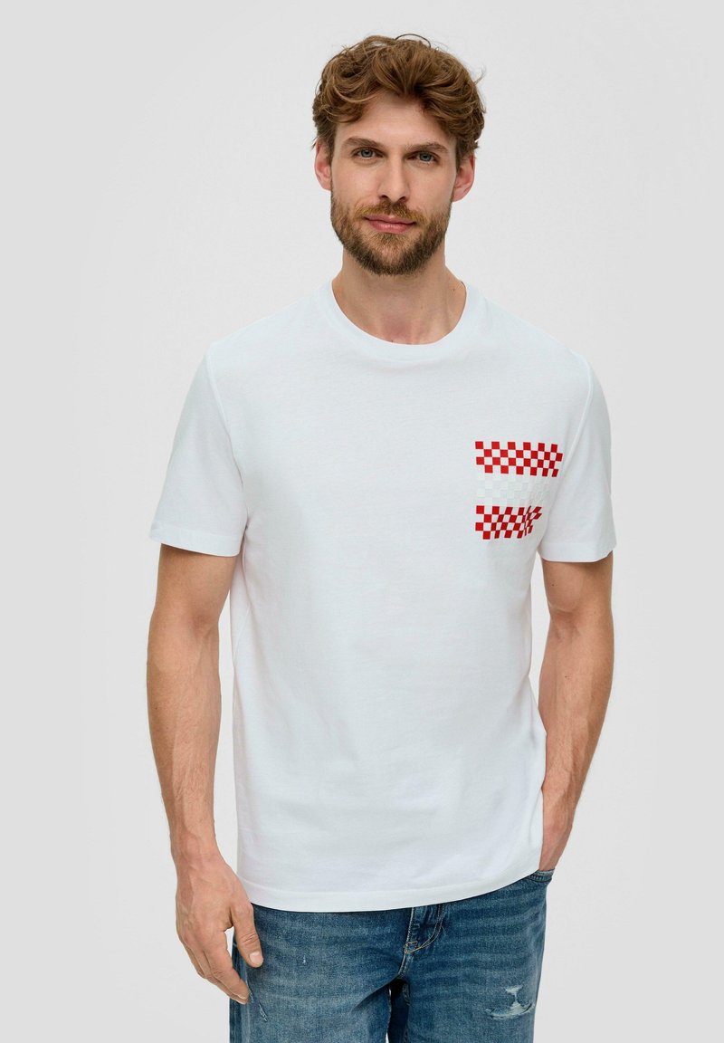 Camiseta de algodón blanca con escote redondo y mangas cortas, que presenta un patrón de cuadros rojos y blancos en el área del bolsillo del pecho izquierdo.