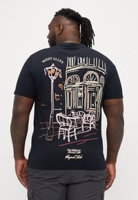 Tricou din bumbac negru cu un grafic care ilustrează o scenă de cafenea cu un felinar, scaune și o clădire. "West Alley" este imprimat deasupra desenului.