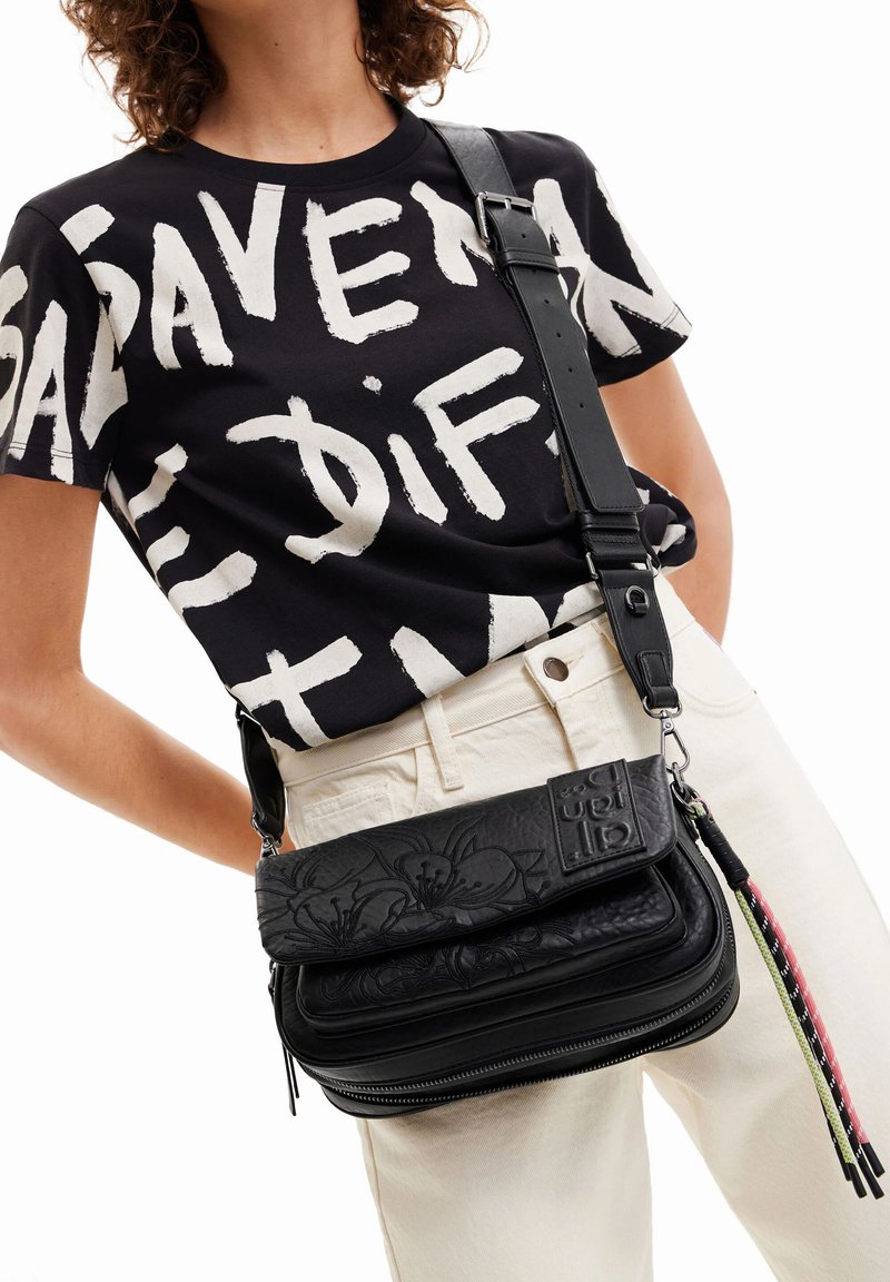 Schwarze Leder-Umhängetasche mit geprägtem Blumendesign, verstellbarem Riemen und Reißverschluss, mit bunten Quastenakzenten.