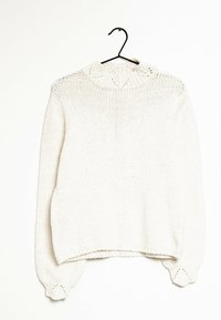 Suéter de punto color crema con mangas largas, dobladillo y puños acanalados, y un cuello redondo texturizado colgando de una percha negra.