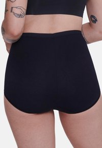 Culottes noires en coton taille haute avec une texture lisse et des bords festonnés, présentant un design sans coutures et un matériel minimal.