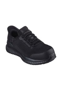Zapatilla deportiva negra con parte superior de malla, punta redondeada, suela gruesa y cordones elásticos. Presenta paneles texturizados y un diseño de talón contorneado.