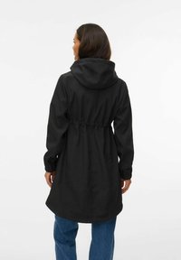 Must kapuutsiga jope, millel on peenike vöökoht, pika varrukad ja elastsed mansetid. Omadusena on sirge lõige ja jope ulatub keskreieni, mida on kombineeritud siniste teksadega.