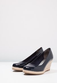 Námořnické úzké lakované wedges se splétaným juty podpatkem, zaoblenou špičkou a hladkým povrchem. Vnitřek je podšitý měkkou tkaninou.