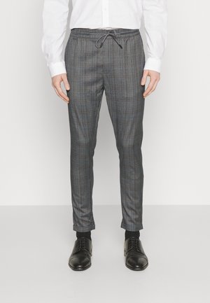 Grijze geruite broek met een trekkoord in de taille, taps toelopend ontwerp en een gladde textuur. Gecombineerd met zwarte dresschoenen.