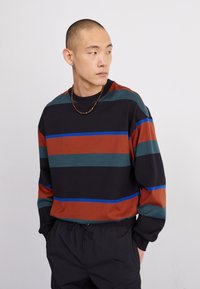 Gestreept sweatshirt in zwart, roest, groen en blauw. Gemaakt van zachte stof met een ronde halslijn en lange mouwen, met een relaxte pasvorm.