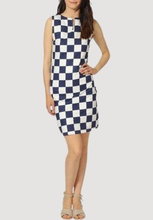 Vestido sin mangas a cuadros en navy y blanco con escote en forma de llavero, diseño ajustado y detalle fruncido en el costado. Lleva unas sandalias beige con tiras.