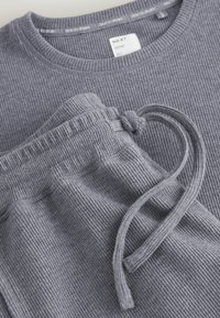 Felpa grigia a coste e pantaloni jogger abbinati con coulisse. Tessuto morbido, design casual, con l'etichetta "è tempo di sognare."