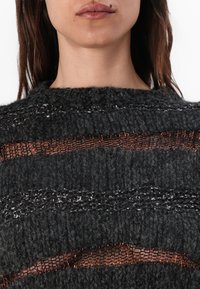 Dark gray knitted sweater with horizontal sheer mesh stripes and metallic accents. Textured fabric with a rounded neckline.